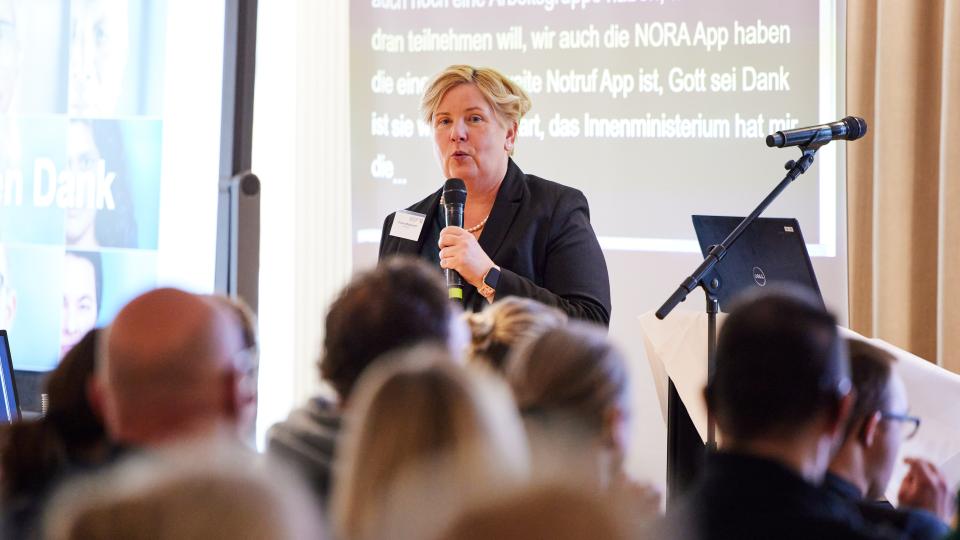 Claudia Middendorf spricht in ein Mikrofon vor einer Menge von Menschen
